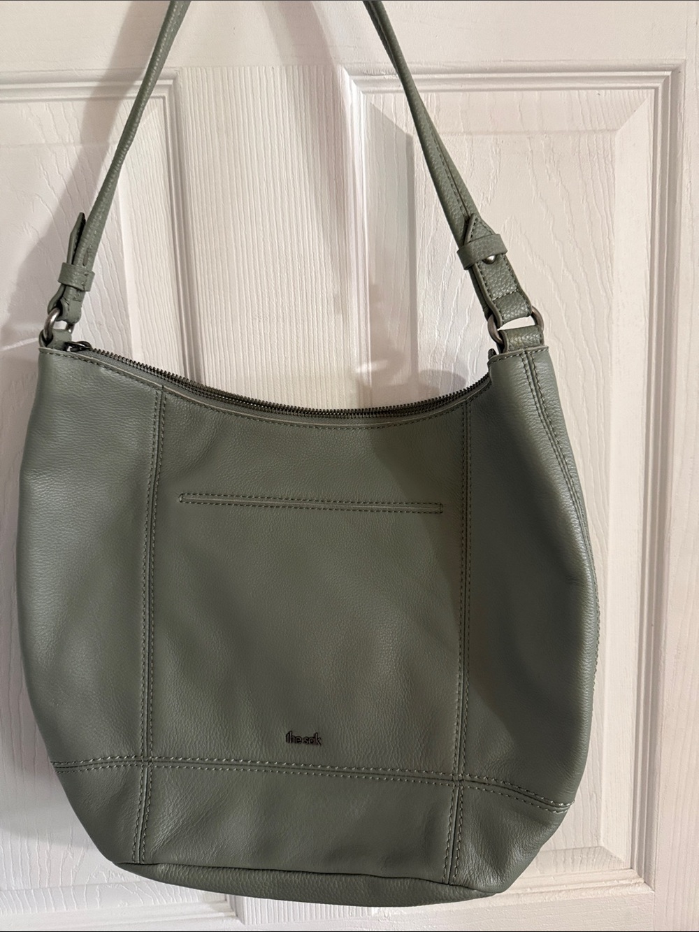 The Sak olive green leather hobo bag with clothes on the top